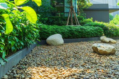 Bahçede parlak yeşil çimlerle kesişen patikalı bahçe tasarımı. Renkli çalılarla peyzaj tasarımı. Bahçe bakımı servisi. Evin yanındaki bahçe birçok küçük taşla dolu..