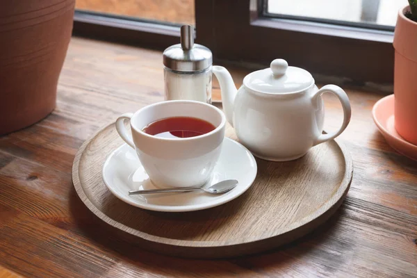 木製の窓枠に赤いフルーツティー ティーポット 砂糖ボトル付きのカップ カフェ 正面図 — ストック写真