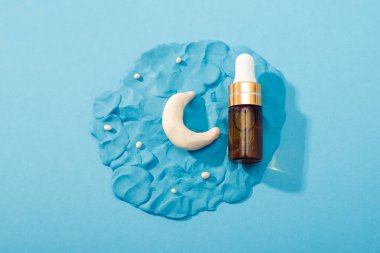 Gece yüz bakımı için kozmetoloji ürünü. Pipetli cam şişede serum, kil ay ve mavi arka planda yıldızlar. Bakım için gerekli yağ. Cilt bakımı, nemlendirici güzellik, model.