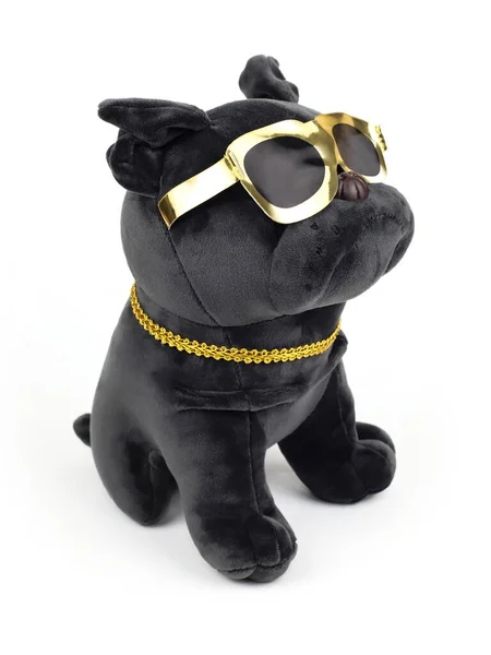 Plush soft black pug dog toy with golden sunglasses isolated on white background. Close-up. Three quarter portrait Diagonal snapshot.