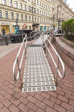 Saint-Petersburg, Rusya - 05.29.2022: Sokaktaki metro girişinde tekerlekli sandalyeler için çelik rampa. İnsanlar için metal rampa.