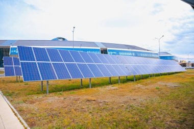 Büyük şehirde çimenlikteki güneş enerjisi panelleri. Dünya çapında küresel ısınmayı azaltmak için güneş ışığından gelen temiz enerji ve çevre enerjisini kullanma kavramı. Yaşam biçimi