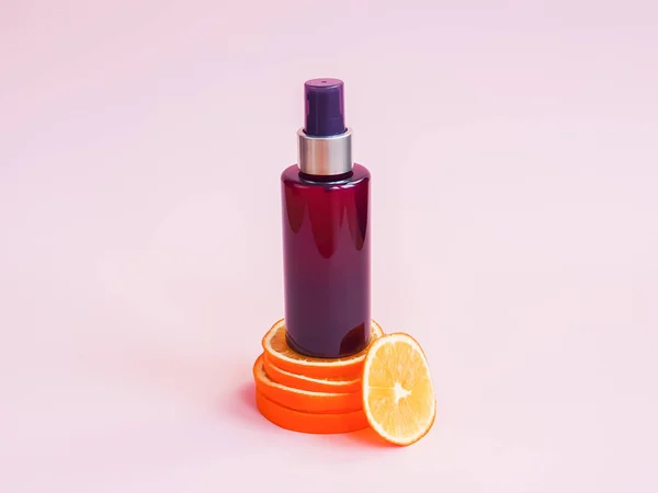 Mockup cosmetic spray bottle and orange slices on pink background. Cream bottle with vitamin c. Body or hair natural oil, skincare, sanitizer, sunscreen, moisturizer, micellar water. front view