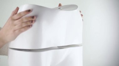 Manken kadın fileto monte ediliyor, arka tarafı küçük. Siyah tırnaklı genç bir kadın, kadın figürlü manken topluyor..