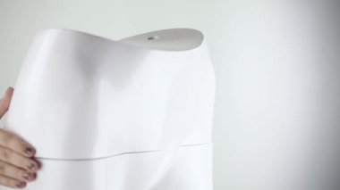 Manken kadın fileto monte ediliyor, arka tarafı küçük. Siyah tırnaklı genç bir kadın, kadın figürlü manken topluyor..