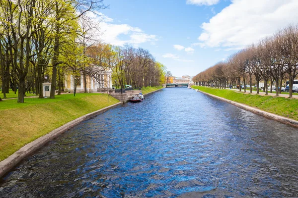 Avrupa şehrinde su kanalı nehri, çimen, park, sıra ağaç dikme. Yaz. St. Petersburg, Rusya - 05.29.2022.