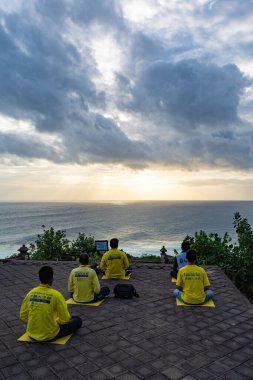 Bali, Indonesia - 3 August 2017: Four people from Falun Dafa religion meditate in the Uluwatu Beach, Bali, Indonesia clipart