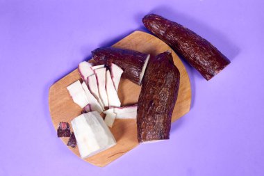 Taze Organik Cassava Kökü, Manioc Esculenta, yuca Mor arka planda, el masasında