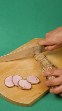 Kadın eli bıçaklı, yeşil arka planda tahta tahtada malanga küp kesiyor.