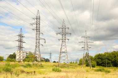 Mavi gökyüzündeki sütunlarda yüksek voltajlı elektrik hatları