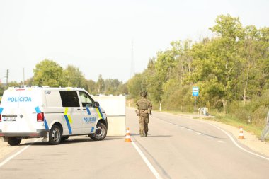 SILENE, LATVIA - 19 Eylül 2023: Kapsamlı Devlet Savunma Tatbikatı İsimleri 2023. Mobil kontrol noktasında takım çalışması koordinasyonu. Polis makinesi beton blokların yanında.