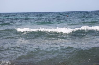 Deniz dalgaları sahilin arka planında. Yazın sahilde deniz dalgaları. Deniz dalgalarının fotoğrafı