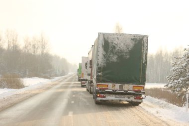 KRASLAVA DISTRICT, LATVIA - 1 Aralık 2023: Letonya-Belarus sınırındaki yük kamyonları kontrol noktası Paternieki 'den önce. Araçlar dondurucu soğukta karla kaplı bir yolda duruyorlar.