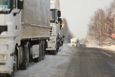 KRASLAVA DISTRICT, LATVIA - 1 Aralık 2023: Letonya-Belarus sınırındaki yük kamyonları kontrol noktası Paternieki 'den önce. Araçlar dondurucu soğukta karla kaplı bir yolda duruyorlar.