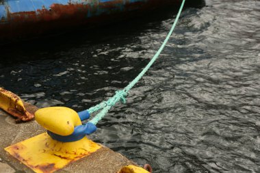 Tekne limana demirlemiş. Deniz gemisi iskeledeki metal kordona beyaz bir iple bağlanmış, yakın plan. Doktor ve tekne parkı. Denizde seyahat et