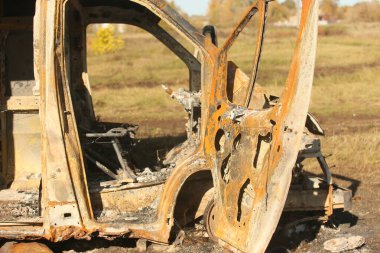 Yolun kenarında büyük, eski, yanmış bir otobüs. Yan görünüm