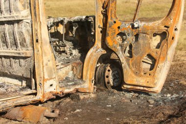 Yolun kenarında büyük, eski, yanmış bir otobüs. Yan görünüm