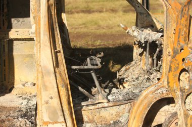 Yolun kenarında büyük, eski, yanmış bir otobüs. Yan görünüm
