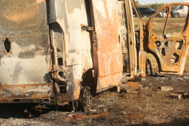 Yolun kenarında büyük, eski, yanmış bir otobüs. Arka görünüm