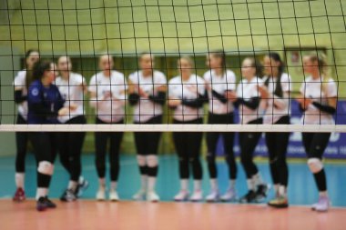 Voleybol oyuncularının arka planda bulanıklaştığı kapalı bir sahada voleybol ağı