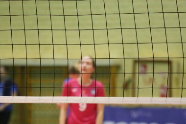 Voleybol oyuncularının arka planda bulanıklaştığı kapalı bir sahada voleybol ağı