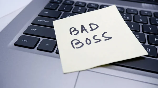 ノートパソコンに貼り付けるノートパッドに書かれた悪い上司は 企業の世界の悪い環境を表します — ストック写真