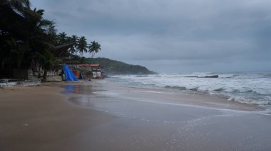 Muson yağmurlarında kalabalık ve boş Anjuna plajı manzarası.