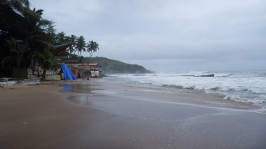 Muson yağmurlarında kalabalık ve boş Anjuna plajı manzarası.