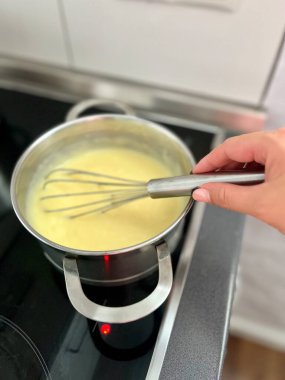 Kadın eli kaşıkla metal tavada kaynar çorba karıştırıyor. Buhar yavaşça sıcak sudan yükseliyor.. 