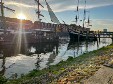 Bremen, Germany - September 11th, 2024 - Cargo ship on the river Weser at sunrise with construction site and cranes in the distance.  clipart