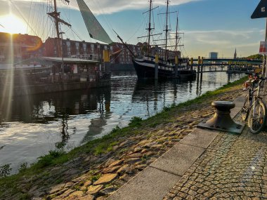 Bremen, Germany - September 11th, 2024 - Cargo ship on the river Weser at sunrise with construction site and cranes in the distance.  clipart