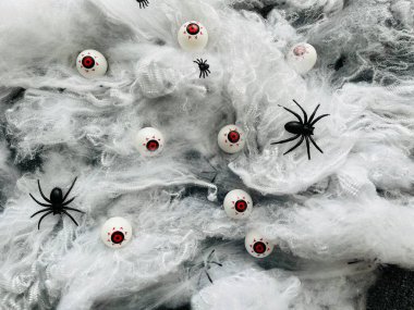 Eyeball with red blood vessels in the legs of an arthropod black spider in a white web on a black background. Halloween holiday. Background for advertising. Creepy gouged eye.  clipart