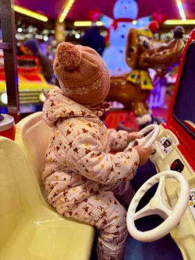 Sıcak kırmızı ceketli mutlu küçük kız ve örgü ören ren geyiği şapkalı atlıkarınca sürücüsü geleneksel Alman Noel pazarına aile gezisi sırasında. 