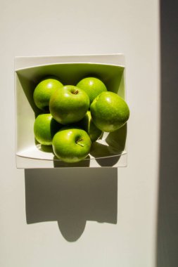 Kasede bir çift yeşil elma. Yeşil elmalar. Sert ışık. Gölge.