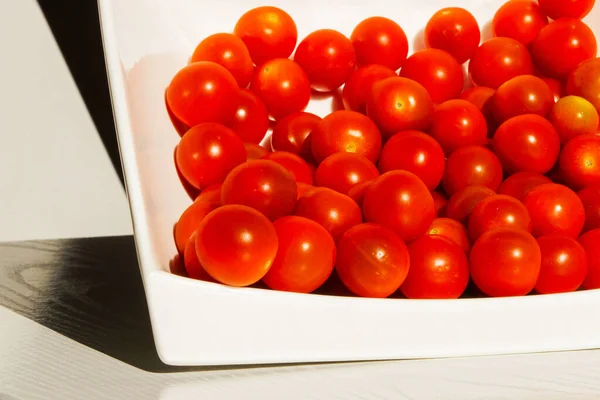 Cherry tomatoes. Cherry tomatoes in a white plate. Hard light. Bright light and shadow.