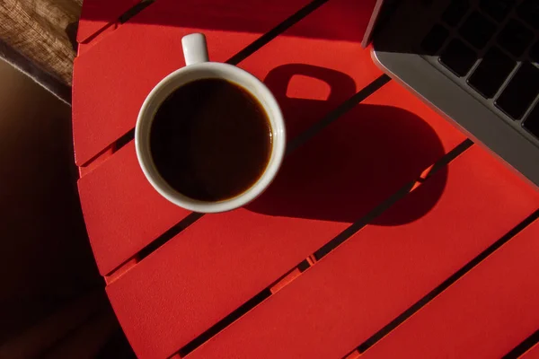 Чашка Кофе Ноутбук Красном Столе Светло Жесткое Освещение Тени Вид — стоковое фото