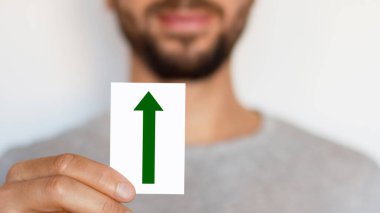 Man holding up arrow sign. Green arrow pointing up. The male. Direction. Motion. Where. Growth.
