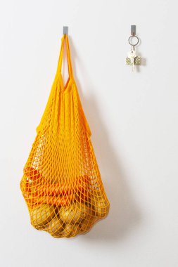 mesh grocery bag. Reusable bag. Vegetarianism, raw food diet, conscious consumption, grid. orange mesh bag  keys on the wall hanging on a hook. Potato bag. Raw potatoes.