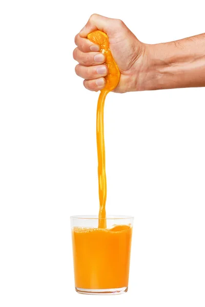 A man's hand squeezes a ripe orange into a glass. A man is holding and squeezing an orange. Orange juice is pouring. Isolated on a white background.