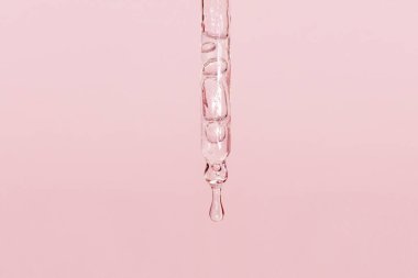 Sıvı damlayan kozmetik pipeti ve pembe arka plan, serum, serum, jel, vitamin, su, yağ damlaları