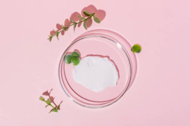 Pembe arka planda kremalı Petri kabı. Bitkilerle çevrili.