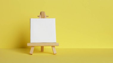 Mini painting on an easel on a yellow background. Directly
