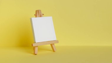 Mini painting on an easel on a yellow background. side