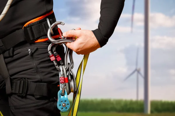 High-altitude equipment, carabiners, block rollers, on a man\'s belt. Telecommunications, work at height, industrial mountaineering, height, insurance. Close-up. Wind generator.
