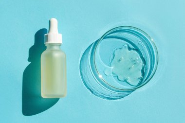 Petri kabı. Şeffaf jelle. Kozmetik şişesi. Bir pipetle. Mavi bir arkaplanda.