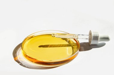 Petri kabı. Sarı sıvıyla. Çözümle. Kozmetik pipeti. Beyaz bir arkaplanda.