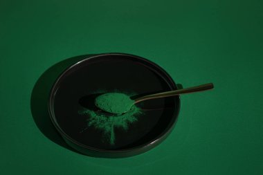 Siyah arka planda kaşıkta taze spirulina algleri tozu, yeşil arka planda, organik spirulina tozu.