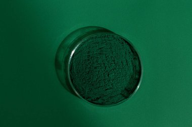 Yeşil zemin üzerinde taze spirulina yosunları, petri kabında, yeşil arka planda, organik spirulina tozu.