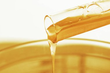 Süzülen altınla test tüpü. Parıltı, cila, sıvı. Çekirdekler. Kozmetik ve sıvıların laboratuvar araştırması. Altın kaplama mevcut jel.