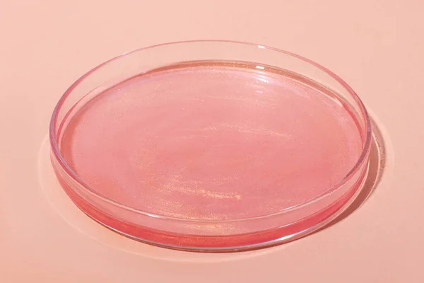 Liquid rose gold. Or a pink liquid with glitter. In a Petri dish. Laboratory research of cosmetics, gel, medicine. Chemistry